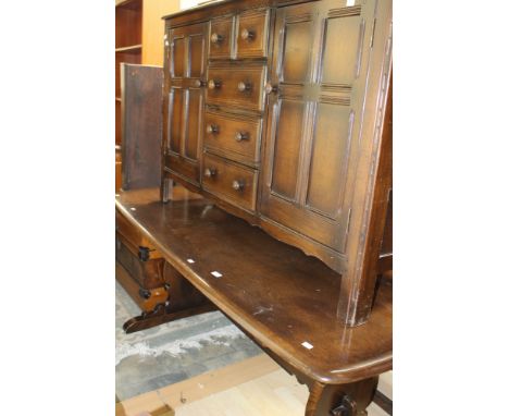 An Ercol oak topped elm trestle dining table, together with a set of eight dining chairs, together with a matching oak sidebo