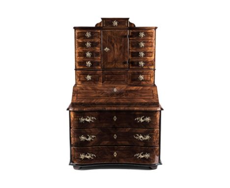 AN AUSTRIAN WALNUT-VENEERED SECRÉTAIRE-ON-CHEST in two parts, the shaped moulded top surmounted by a short drawer, a hinged d