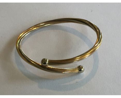 A stamped 750 three colour twisted bangle, with ball terminations, 17.4gms.