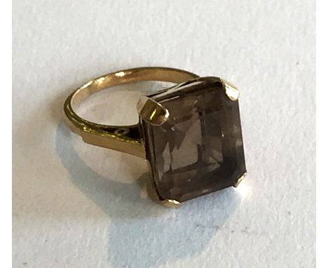 A smoky quartz set single stone ring, the step cut smoky quartz four claw set to raised gallery and plain band.