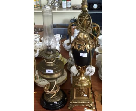 A reproduction brass and black twin handled standard lamp, having ornate decoration together with a vintage paraffin lamp con