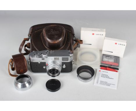 A Leica M2 camera, No. 989771, circa 1960, with Leitz Elmar f=5cm 1:2.8 lens, Nr. 1438292, with leather case, Leitz lens hood