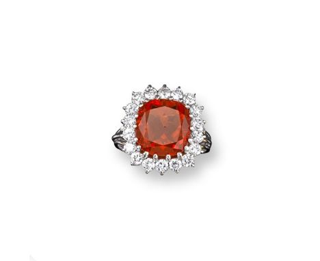 A fire opal and diamond cluster ring, the cushion-shaped opal is set within a surround of eighteen round brilliant cut diamon