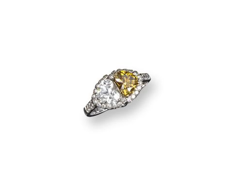 A yellow and white diamond ring, the two heart-shaped diamonds are set in white gold within a border of smaller circular-cut 