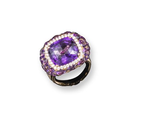 A modern amethyst and diamond cluster ring, centred with a cushion-shaped amethyst within a border of round brilliant-cut dia
