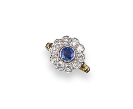 A sapphire and diamond cluster ring, the circular cut sapphire is millegrain set within a surround of ten smaller circular cu