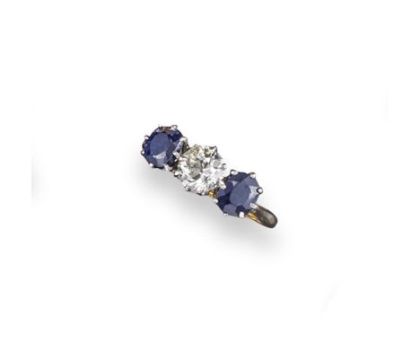 A diamond and sapphire three stone ring, the circular cut diamond is set with two oval shaped sapphires, in gold. Size M. Box