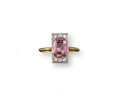 An Edwardian pink topaz and diamond set plaque ring, the oval shaped topaz set with six small diamonds in platinum and gold. 