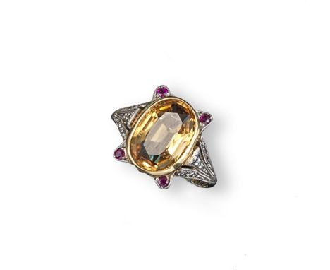 An early 20th century topaz, ruby and diamond ring by Mrs Newman. The oval-shaped topaz is set with four small circular-cut r