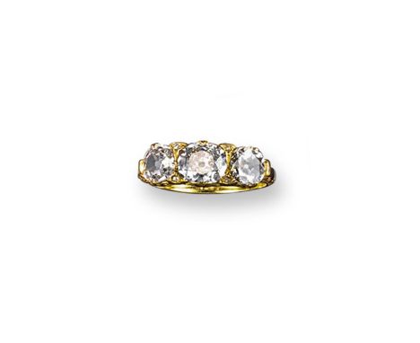 A diamond three stone ring, the three graduated slightly oval-shaped diamonds are set in yellow gold with pierced scroll shou