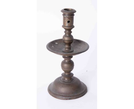 An antique Dutch brass single candlestick with wide drip tray, height 22cm.