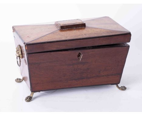 A mahogany tea caddy of sarcophagus style on brass feet.