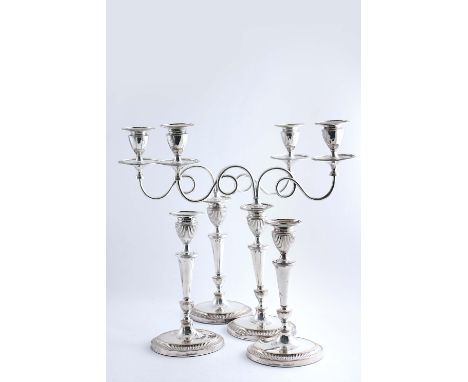 A SET OF FOUR OLD SHEFFIELD PLATED CANDLESTICKS on navette-shaped bases with fluted capitals, reeded borders, together with a