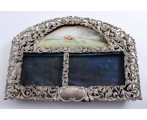 A VICTORIAN OPENWORK PHOTOGRAPH FRAME with an arched top, on a hunting theme with mounted huntsmen, horns, a saddle, a fox ma