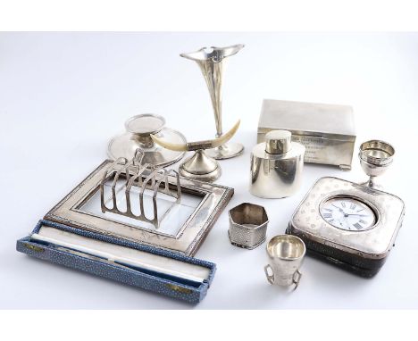 A MIXED LOT:- A travelling timepiece, a capstan inkwell, a cigarette box, inscribed, a frame mount, a spill vase, a tea caddy