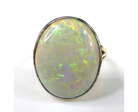 A 15ct gold opal dress ring, featuring an oval white opal cabochon with blue, green and red colour flashes, within a bezel se
