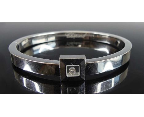 A Chopard 18ct white gold Happy Diamond oval hinged bangle, featuring a 2.2mm round brilliant cut diamond in a heavy square s