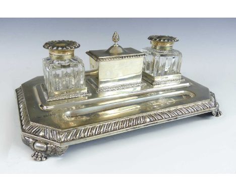 A late Victorian silver inkstand, comprising a stepped rectangular stand with canted corners, reeded edge and four winged lio