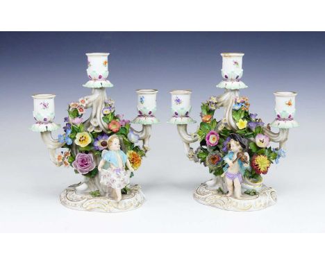 A pair of Meissen porcelain three-branch table candelabra, 19th century, each decorated with two children before a floral enc
