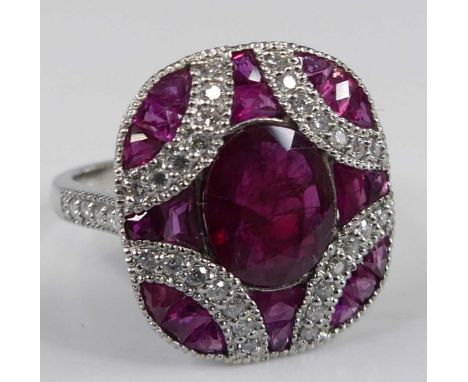 A platinum, ruby and diamond oblong cluster ring, comprising a centre oval ruby within a border of 20 trillion and trapeze cu