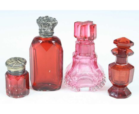 A Victorian scent bottle, having a facet cut ruby glass body and floral embossed white metal hinged cover opening to a glass 