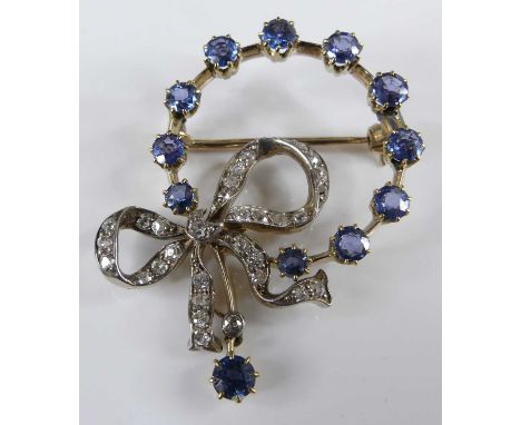 A yellow and white metal, sapphire and diamond open circular brooch, with bow detail and a roller catch fastening, featuring 