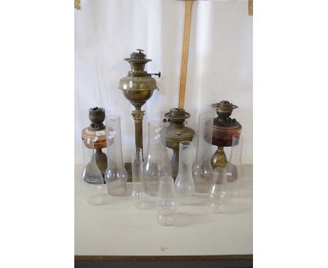 A Victorian oil lamp with glass reservoir, various glass chimneys, also two further lamps and a lamp with corinthian column o