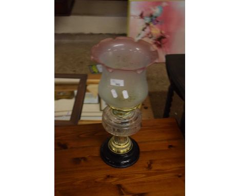 A vintage oil lamp with pink tinted shade