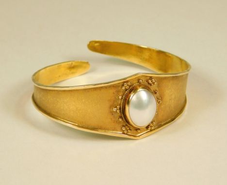 GOLD BANGLE. A 14ct. bloomed gold bangle, the front set a pearl. Max. depth 2.2cm.