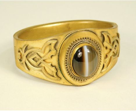 VICTORIAN BANGLE. A Victorian, gilt metal hinged cuff bangle, the front set with banded agate. Max. height 3cm.