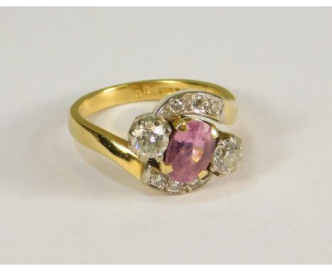 PINK SAPPHIRE RING. An 18ct. gold pink sapphire ring, the oval stone flanked by a pair of diamonds, each of approx. 0.25ct. s