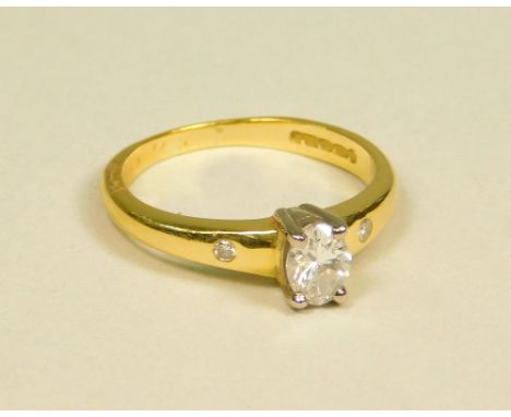 DIAMOND RING. An 18ct. gold diamond ring set an oval brilliant cut diamond, with two small diamonds to either shoulder. Lengt