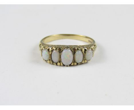 A five stone opal dress ring, the graded cabochons being held in a fancy claw setting above a scroll pierced mount, on a 9ct 