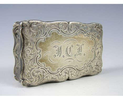 A Victorian silver snuff box, of cusped rectangular section, profusely engraved with scrolling foliate sprigs surrounding a c
