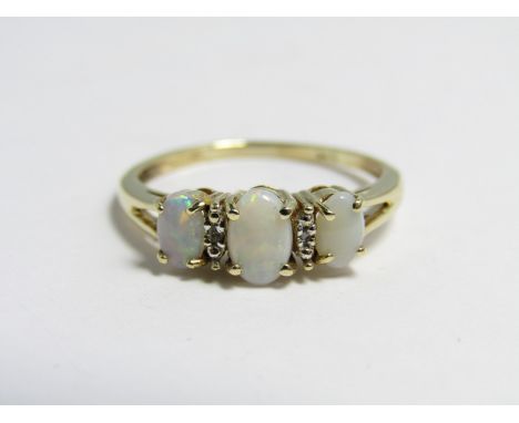A contemporary opal and diamond ring, comprising three oval opal cabochons divided by small diamonds on a 14 ct gold shank
