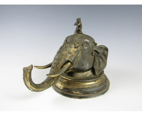 A Victorian electroplate novelty inkwell modelled as an elephant's head, the lid finial modelled as a monkey playing a flute,