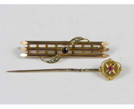 A late Victorian / Edwardian 9ct gold brooch worked ad three parallel bars united by pellets and entwined by a garnet and spl