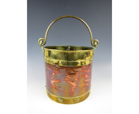 A hand wrought copper and brass planter or coal bin of bucket form with swing handle, 23 cm excluding handle