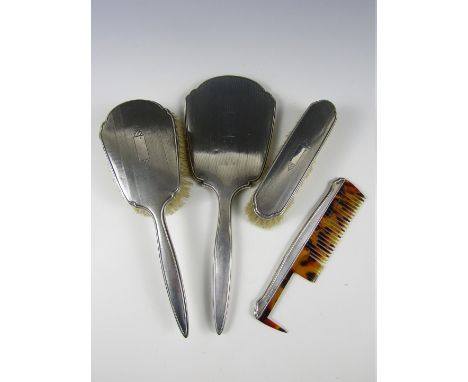 A George V silver four-piece brush, mirror and comb set, each element decorated with engine-turning and bearing a vacant cart