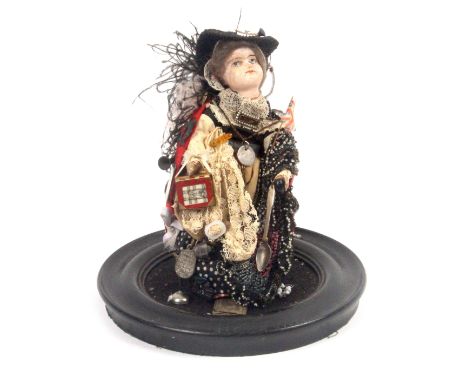 A Victorian pedlar doll, ceramic body with ostrich feather cap and red cloak, the doll with numerous miniature items, some la