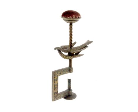 A brass hemming bird clamp, the rectangular leaf decorated frame below a sprung bird and spiral pillar supporting a bowl form