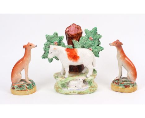 A pair of Staffordshire figures and another, comprising a pair of seated dogs on domed foliate bases, 10.5cms high, and anoth