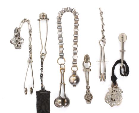 Six tong form skirt lifters, comprising a white metal example on mourning ribbon with chatelaine type mount, the tong 10cms, 