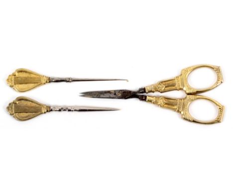 Three French gold mounted sewing tools, comprising a pair of steel bladed scissors with fancy arms and loops, points apart, 9