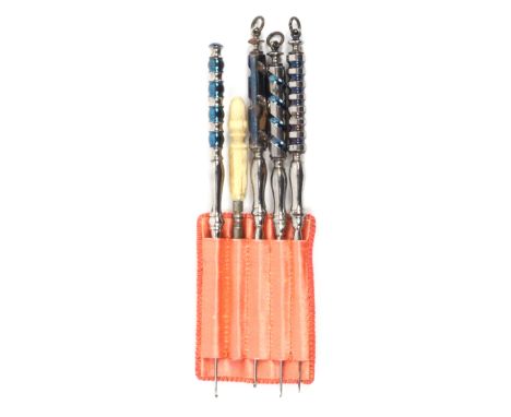 A set of four steel crochet hooks, with variant partly blued steel handles, three with suspension loops, in a pink silk tool 