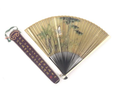 A Chinese fan in embroidered silk Chinese sheath, the fan with paper leaf painted with a lady at a table amid trees and flowe