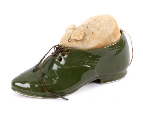 A green ceramic pin cushion in the form of a shoe, the pin cushion infill in the form of a velvet mouse with glass eyes, 12cm