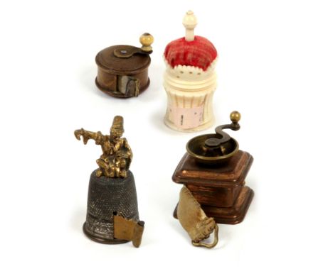 Four tape measures, comprising a novelty metal example in the form of a thimble surmounted by a gilt metal Arab tailor, compl