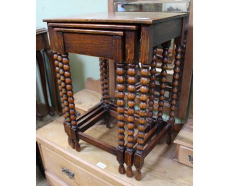 AN OAK NEST OF THREE TABLES the smallest having concealed drawers, on bobbin turned legs 