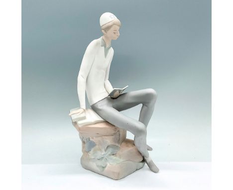 A matte figure of a young man seated on a boulder reading. Lladro backstamp. Artist: Juan HuertaIssued: c. 1970-1985Dimension